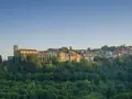 Borgo collinare con chiesa e case in pietra, immerso nel verde. Un luogo incantevole dove scansano cosa vedere, tra storia e natura.