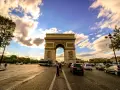 Arco di Trionfo, un'icona di cosa vedere a Parigi, con traffico e nuvole al tramonto.