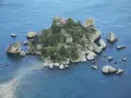Isola Bella, una gemma tra le spiagge Sicilia orientale, con rocce e vegetazione lussureggiante che si tuffano nel mare cristallino.