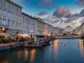 Serata magica a Trieste, uno dei tanti posti belli in Italia. Canale illuminato, palazzi storici e gente ai tavolini all'aperto.