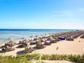 Spiaggia di Marsa Alam con file di ombrelloni e lettini, molo sull'acqua cristallina. Ideale per escursioni e relax.