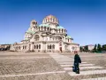 Una donna attraversa la strada davanti alla maestosa Cattedrale Alexander Nevsky, un'icona di cosa fare a Sofia.