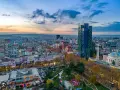Panoramica di Tirana al tramonto, con grattacieli colorati e un parco. Ideale per scoprire cosa vedere a Tirana in 3 giorni.