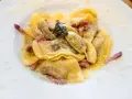 Ravioli ripieni, conditi con pancetta e salvia, un classico dei piatti tipici bergamaschi, spolverati di formaggio grattugiato.