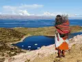 Donna indigena con fascina di legna, vista sul Lago Titicaca, un luogo imperdibile da vedere in Bolivia.