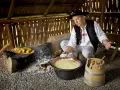 Uomo in abito tradizionale polacco prepara un prodotto tipico della Polonia: formaggio in un paiolo di rame.