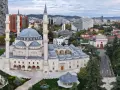 La Grande Moschea e il panorama urbano moderno mostrano dove si trova Tirana, con grattacieli e colline sullo sfondo.