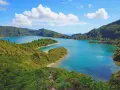 Lago blu circondato da colline verdi lussureggianti, con piccole isole e una spiaggia sabbiosa. Perfetto per capire quando andare alle Azzorre.