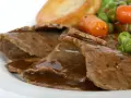 Fette di arrosto con sugo, piselli, carote e patate arrosto, un classico tra i piatti tipici del Regno Unito.
