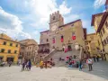 Piazza del Popolo a Cortona, dove si trova questo antico palazzo con torre dell'orologio, animata da turisti e figuranti in costume.
