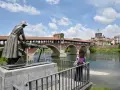 Pavia cosa vedere in un giorno: il Ponte Coperto con la statua della lavandaia e la cupola del Duomo sullo sfondo.