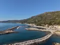 Marina di Pisciotta, con il suo porto turistico e le case aggrappate alla collina verdeggiante, sotto un cielo azzurro.