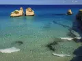 Un mare bello in Italia, con scogli dorati che emergono da acque cristalline e turchesi. Alcune persone nuotano in questo paradiso.