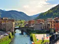 Un pittoresco scorcio di Castelnuovo di Garfagnana con il fiume Serchio che attraversa il borgo, circondato da colline verdi.