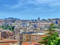 Panoramica di **Caltanissetta cosa vedere**: tetti rossi, palazzi colorati e la cupola di una chiesa sotto un cielo azzurro.
