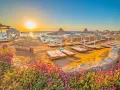 Spiaggia dorata al tramonto, lettini pronti per il relax. Questo è il periodo migliore per andare a Sharm, con fiori viola in primo piano.