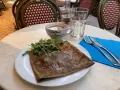 Crepe salata con rucola, una tazza di caffè e un bicchiere d'acqua, un assaggio dei piatti tipici parigini.