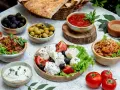 Un banchetto di piatti tipici grecia: feta fresca, olive nere e verdi, salsa di pomodoro, melanzane e pane pita.