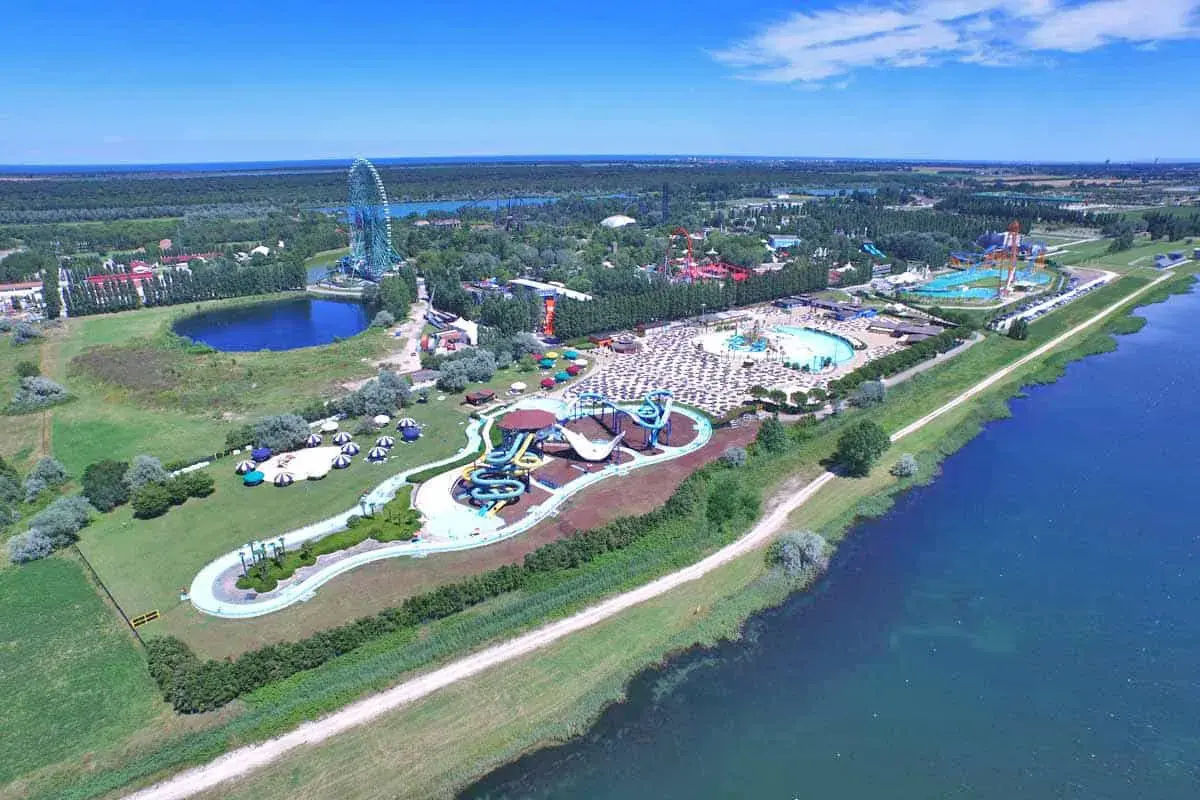 Vista aerea di Mirabilandia, un parco divertimenti con acquascivoli, piscine e una ruota panoramica, situato vicino a un lago.