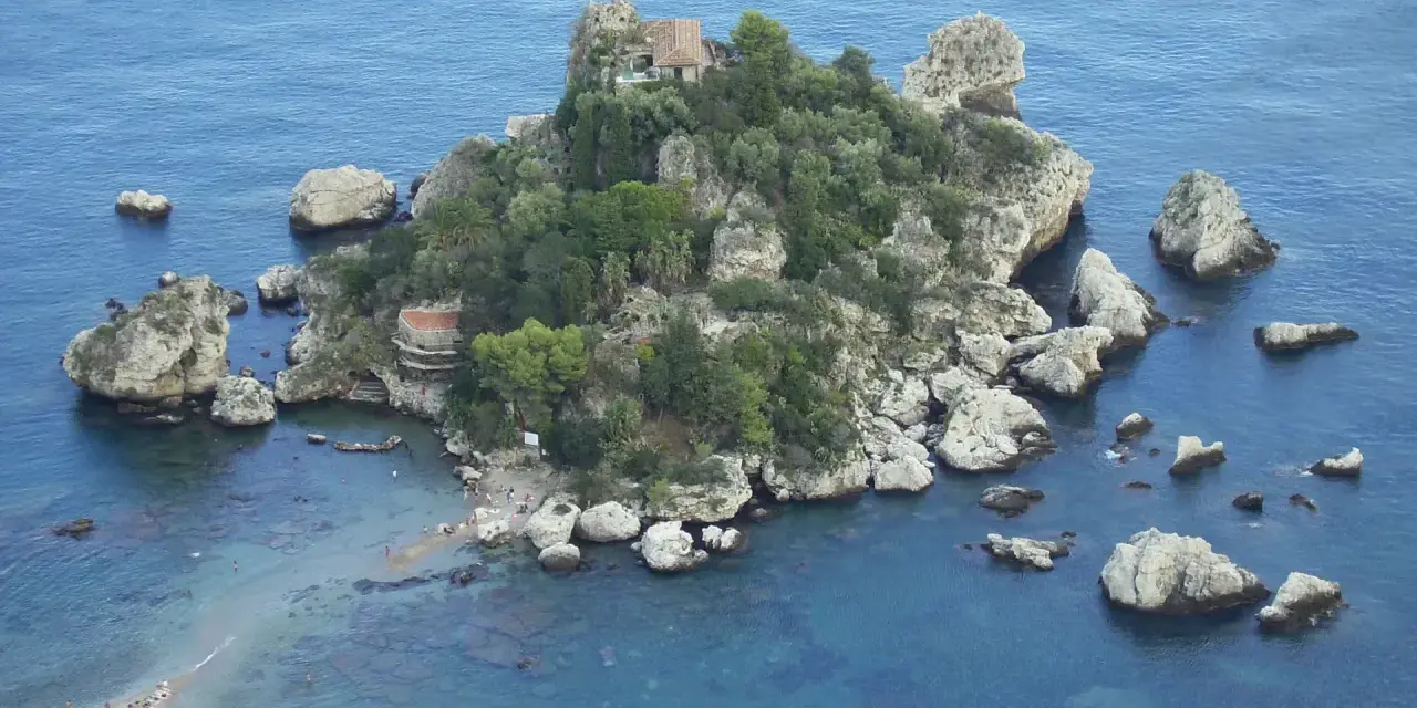 Isola Bella, una gemma tra le spiagge Sicilia orientale, con rocce e vegetazione lussureggiante che si tuffano nel mare cristallino.