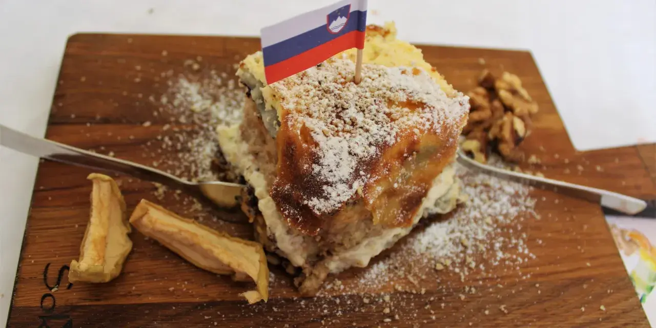 Fetta di torta con bandiera slovena, noci e mele essiccate, un assaggio dei piatti tipici sloveni.