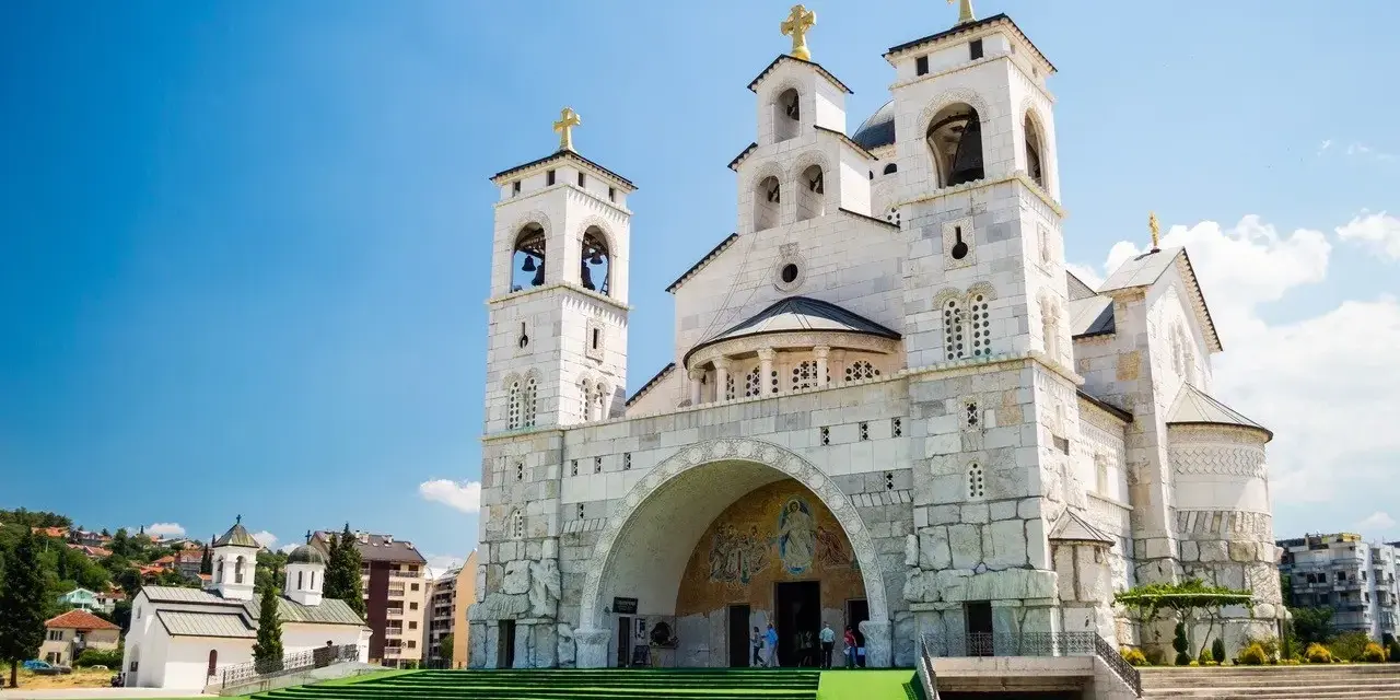 La Cattedrale della Resurrezione di Cristo a Podgorica, cosa vedere: imponente architettura ortodossa con torri campanarie e croci dorate sotto un cielo azzurro.