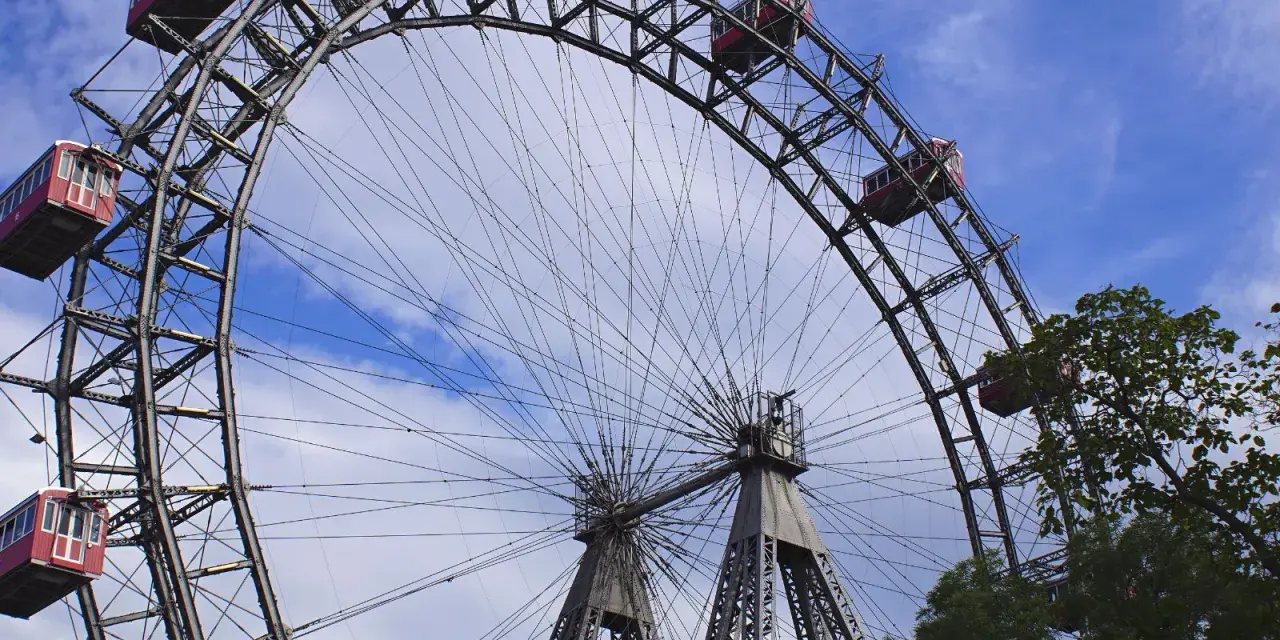 La Ruota Panoramica di Vienna, un'icona per chi cerca cosa vedere a Vienna in 1 giorno, con le sue cabine rosse sotto un cielo azzurro.