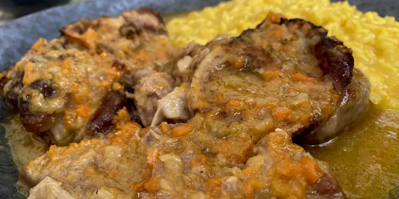Un piatto di ossobuco con risotto alla milanese, un classico da provare per scoprire cosa mangiare a Milano.