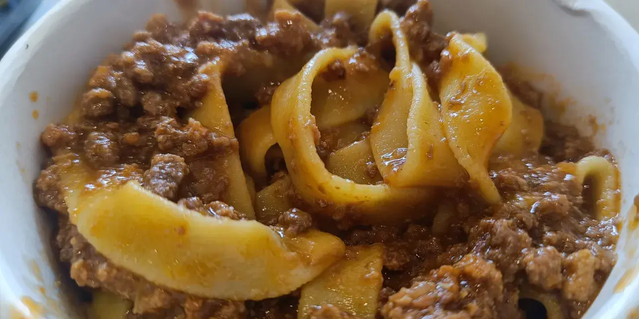 Tagliatelle al ragù, un classico su cosa mangiare a Bologna. Pasta fresca con sugo di carne saporito in una ciotola.
