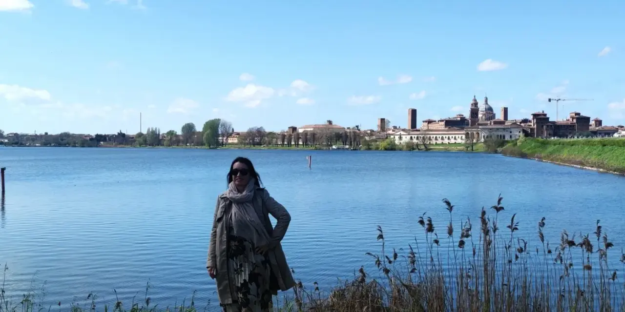 Donna con sciarpa e cappotto ammira il panorama di Mantova, un luogo incantevole da esplorare.