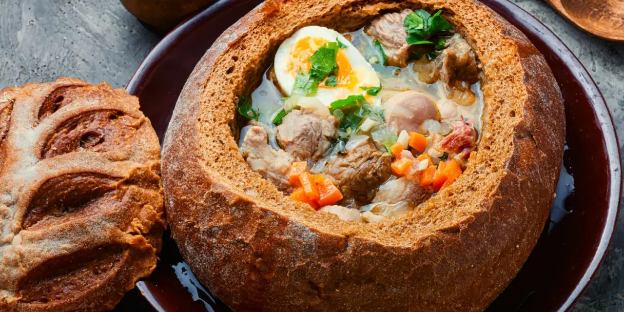 Zuppa polacca servita in una pagnotta scavata, un'ottima idea per cosa mangiare a Cracovia. Carne, uova e verdure in un pane croccante.