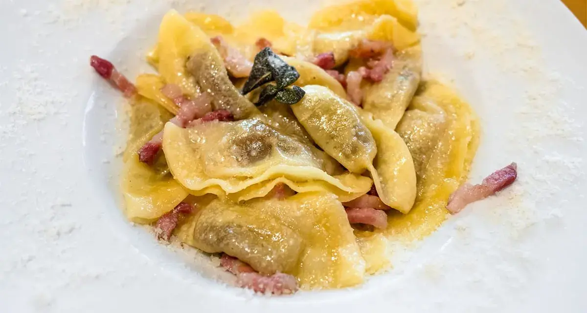 Ravioli ripieni, conditi con pancetta e salvia, un classico dei piatti tipici bergamaschi, spolverati di formaggio grattugiato.