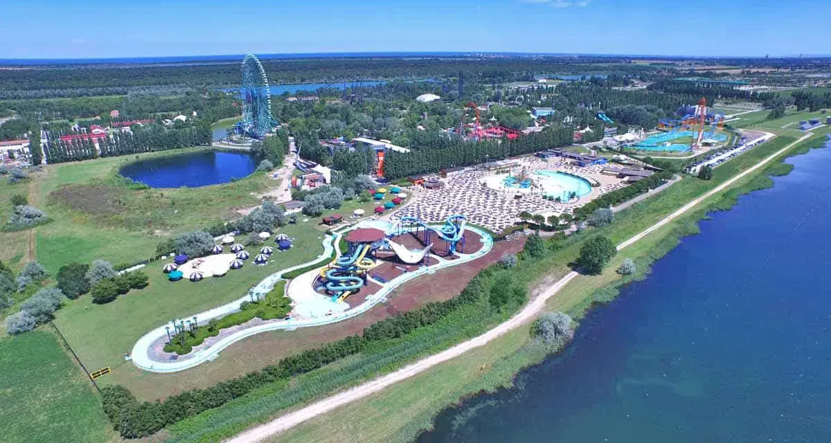 Vista aerea di Mirabilandia, un parco divertimenti con acquascivoli, piscine e una ruota panoramica, situato vicino a un lago.