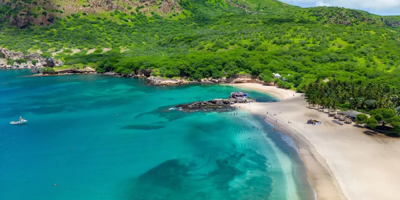 Spiaggia tropicale con acque turchesi e montagne verdi. Un luogo perfetto per scoprire cosa vedere a Capo Verde, tra relax e natura.