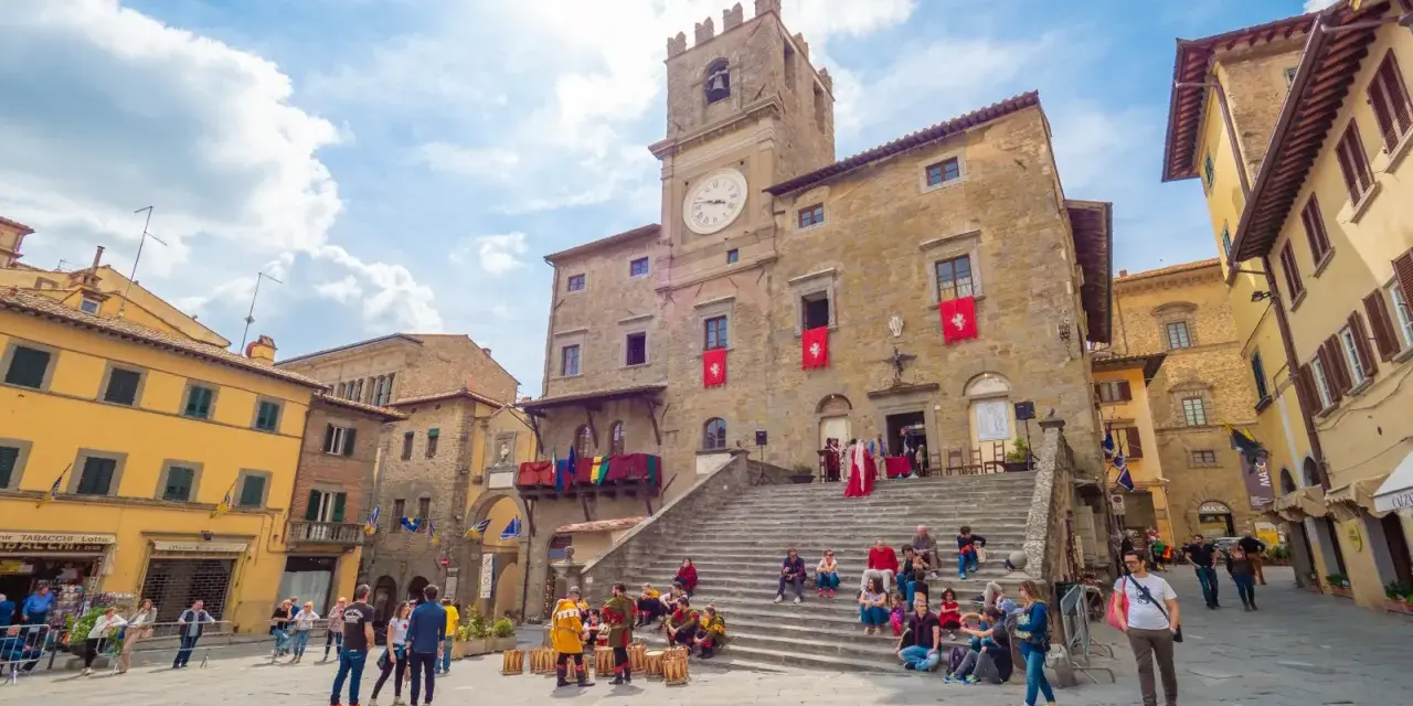 Piazza del Popolo a Cortona, dove si trova questo antico palazzo con torre dell'orologio, animata da turisti e figuranti in costume.