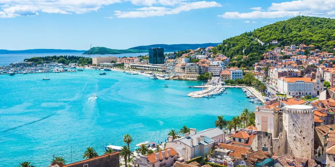 Splendido panorama di Spalato: cosa vedere nel porto turistico, la città con i suoi edifici storici e la collina verdeggiante.