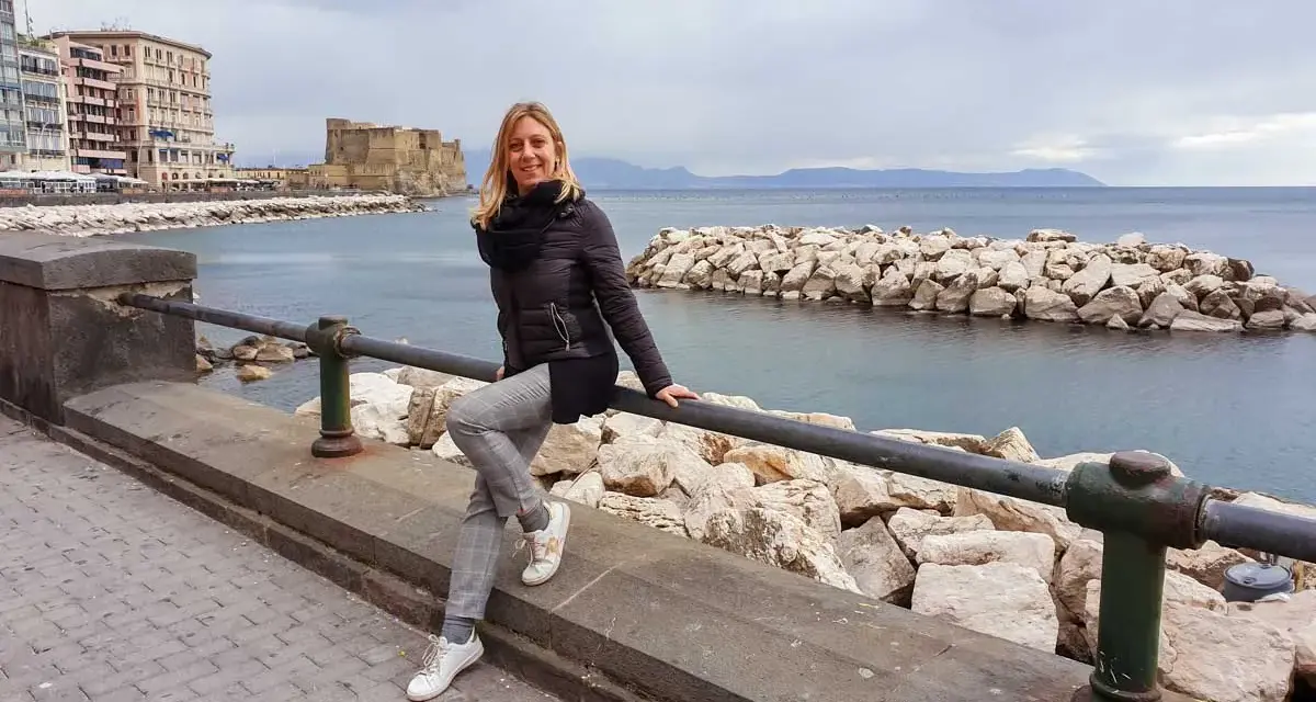 Donna sorridente si gode il panorama di Castel dell'Ovo e del mare, un assaggio di Napoli in 3 giorni.