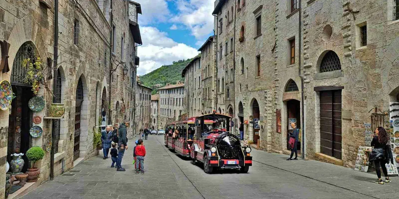 Treno turistico attraversa una strada acciottolata di Gubbio, un'idea per cosa vedere a Gubbio in un giorno.