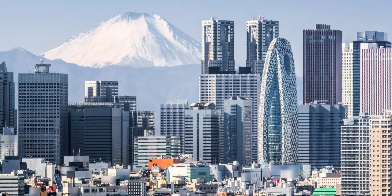 Skyline di grattacieli moderni con il Monte Fuji innevato sullo sfondo, un panorama iconico della citta piu popolata al mondo.