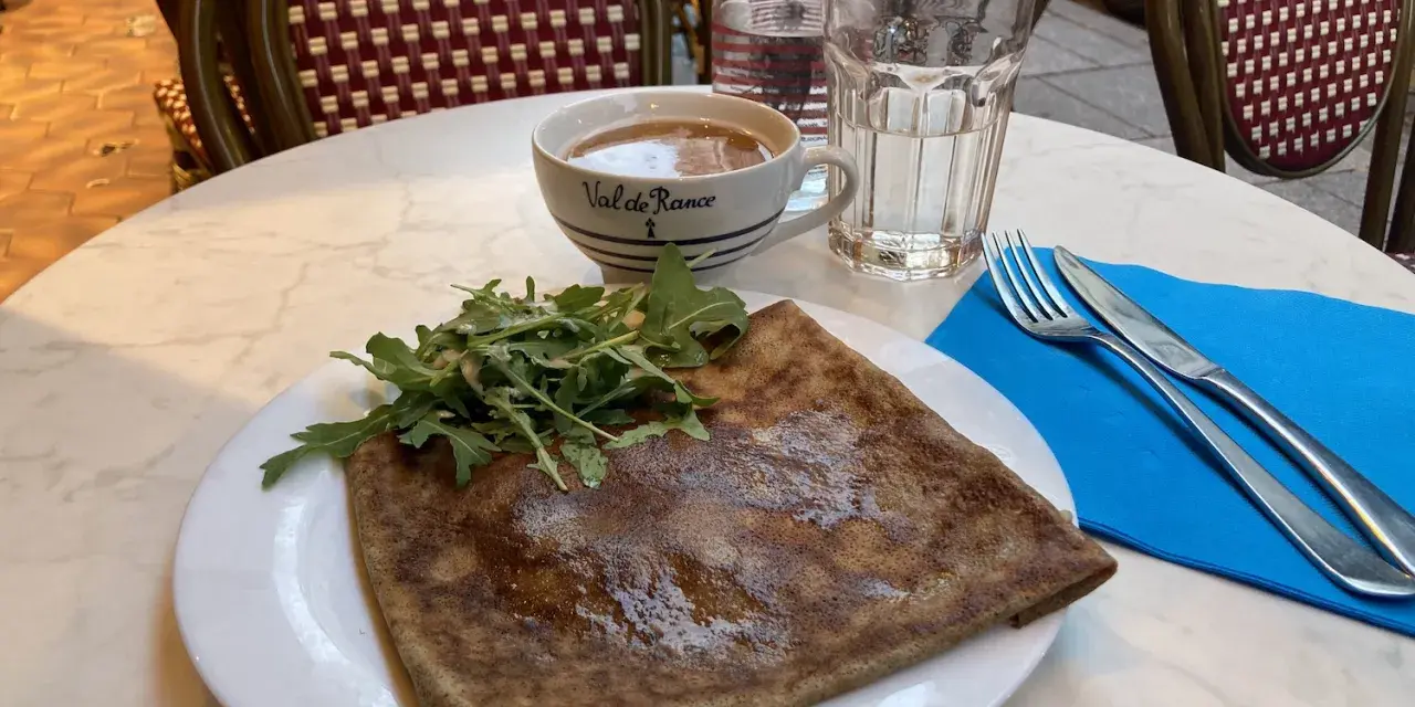 Crepe salata con rucola, una tazza di caffè e un bicchiere d'acqua, un assaggio dei piatti tipici parigini.