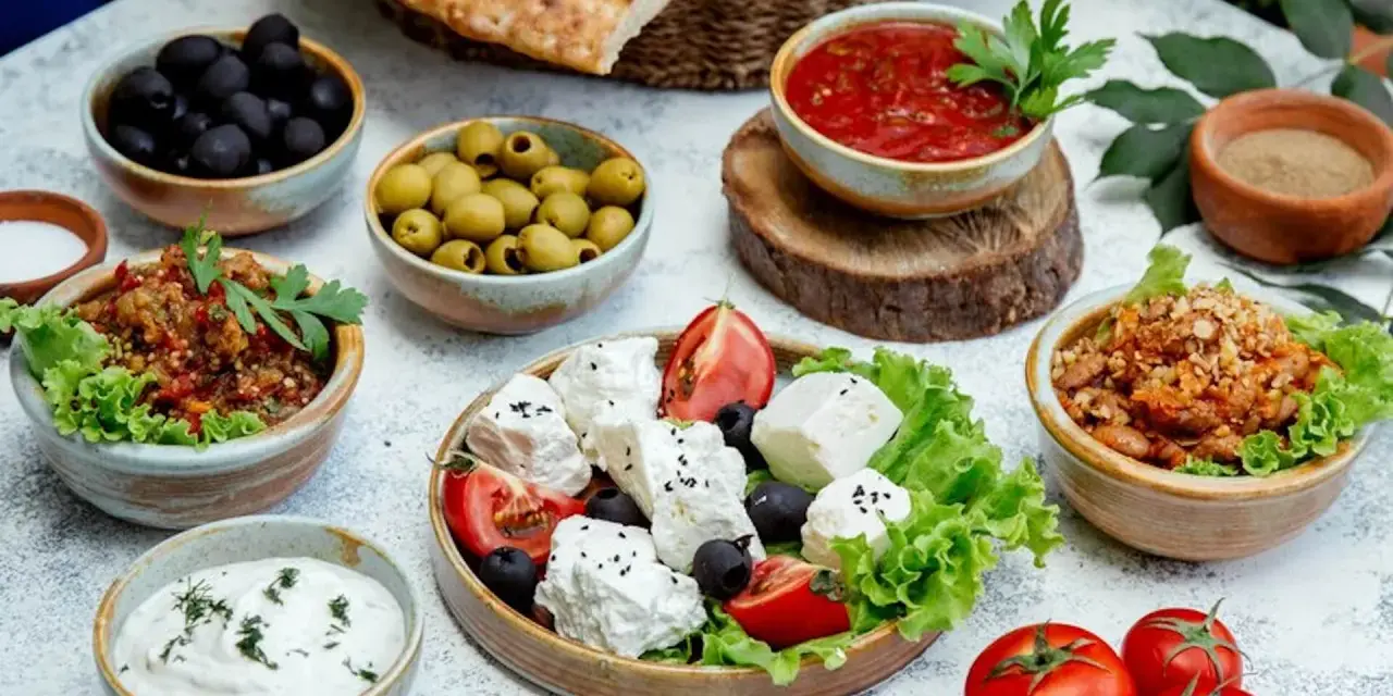 Un banchetto di piatti tipici grecia: feta fresca, olive nere e verdi, salsa di pomodoro, melanzane e pane pita.