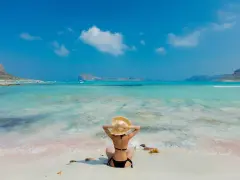 Giovane donna con cappello di paglia ammira il mare turchese, un paradiso tra le isole greche per giovani.