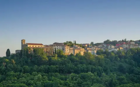 Borgo collinare con chiesa e case in pietra, immerso nel verde. Un luogo incantevole dove scansano cosa vedere, tra storia e natura.