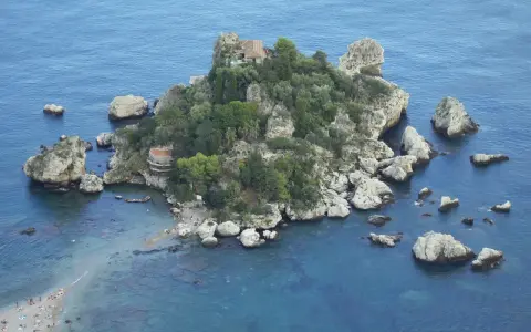 Isola Bella, una gemma tra le spiagge Sicilia orientale, con rocce e vegetazione lussureggiante che si tuffano nel mare cristallino.