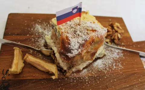 Fetta di torta con bandiera slovena, noci e mele essiccate, un assaggio dei piatti tipici sloveni.