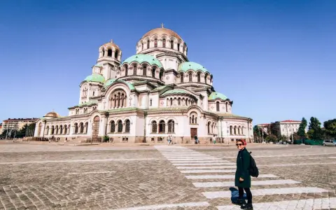 Una donna attraversa la strada davanti alla maestosa Cattedrale Alexander Nevsky, un'icona di cosa fare a Sofia.
