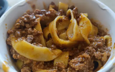 Tagliatelle al ragù, un classico su cosa mangiare a Bologna. Pasta fresca con sugo di carne saporito in una ciotola.