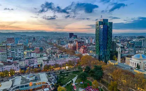 Panoramica di Tirana al tramonto, con grattacieli colorati e un parco. Ideale per scoprire cosa vedere a Tirana in 3 giorni.