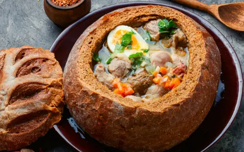 Zuppa polacca servita in una pagnotta scavata, un'ottima idea per cosa mangiare a Cracovia. Carne, uova e verdure in un pane croccante.
