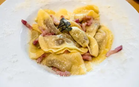 Ravioli ripieni, conditi con pancetta e salvia, un classico dei piatti tipici bergamaschi, spolverati di formaggio grattugiato.